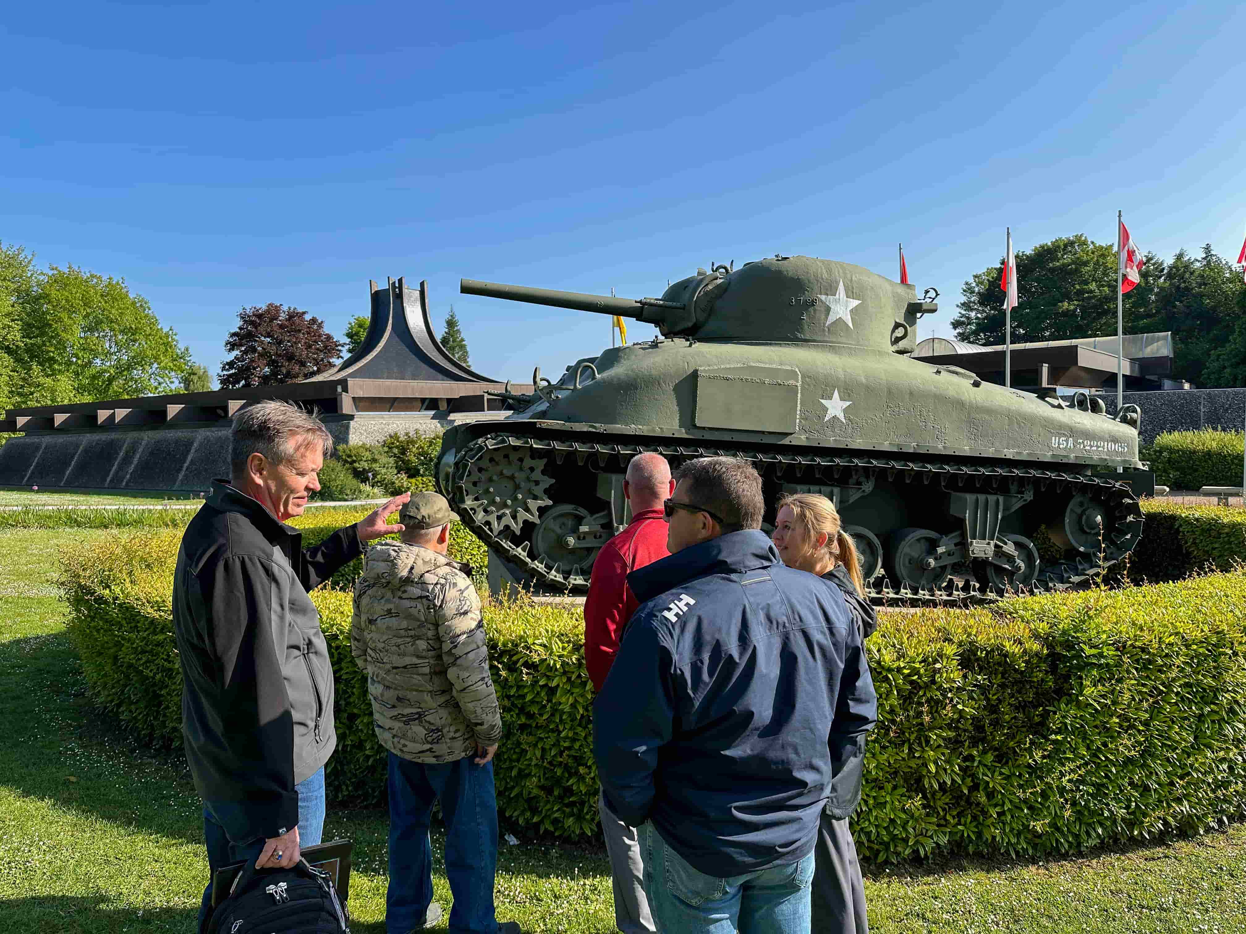 Travelers gathered beside a WWII Sherman tank at a Normandy museum on a Beyond the Beachhead tour