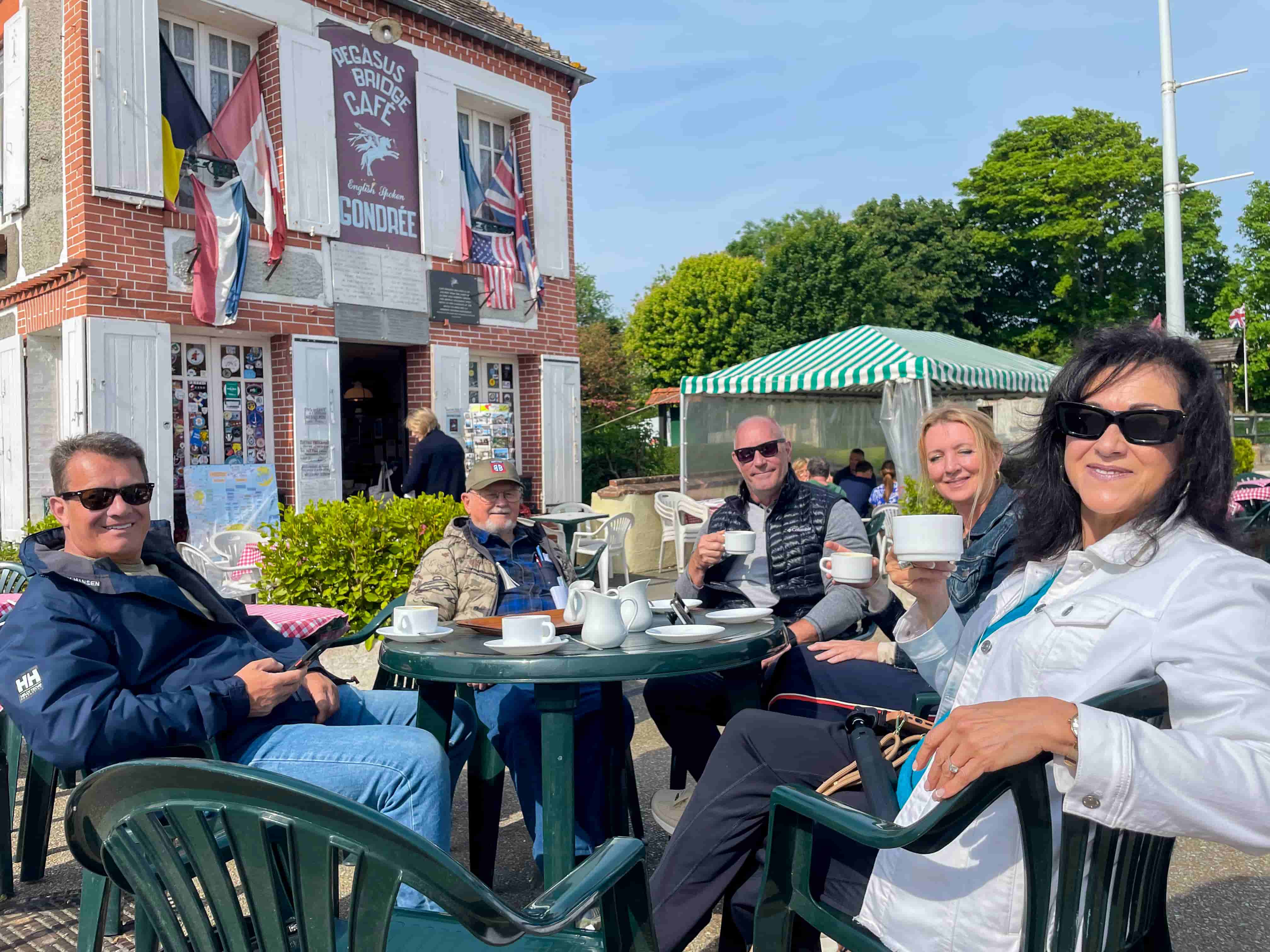 Tour group having coffee outside the historic Cafe Gondree at Pegasus Bridge, Normandy