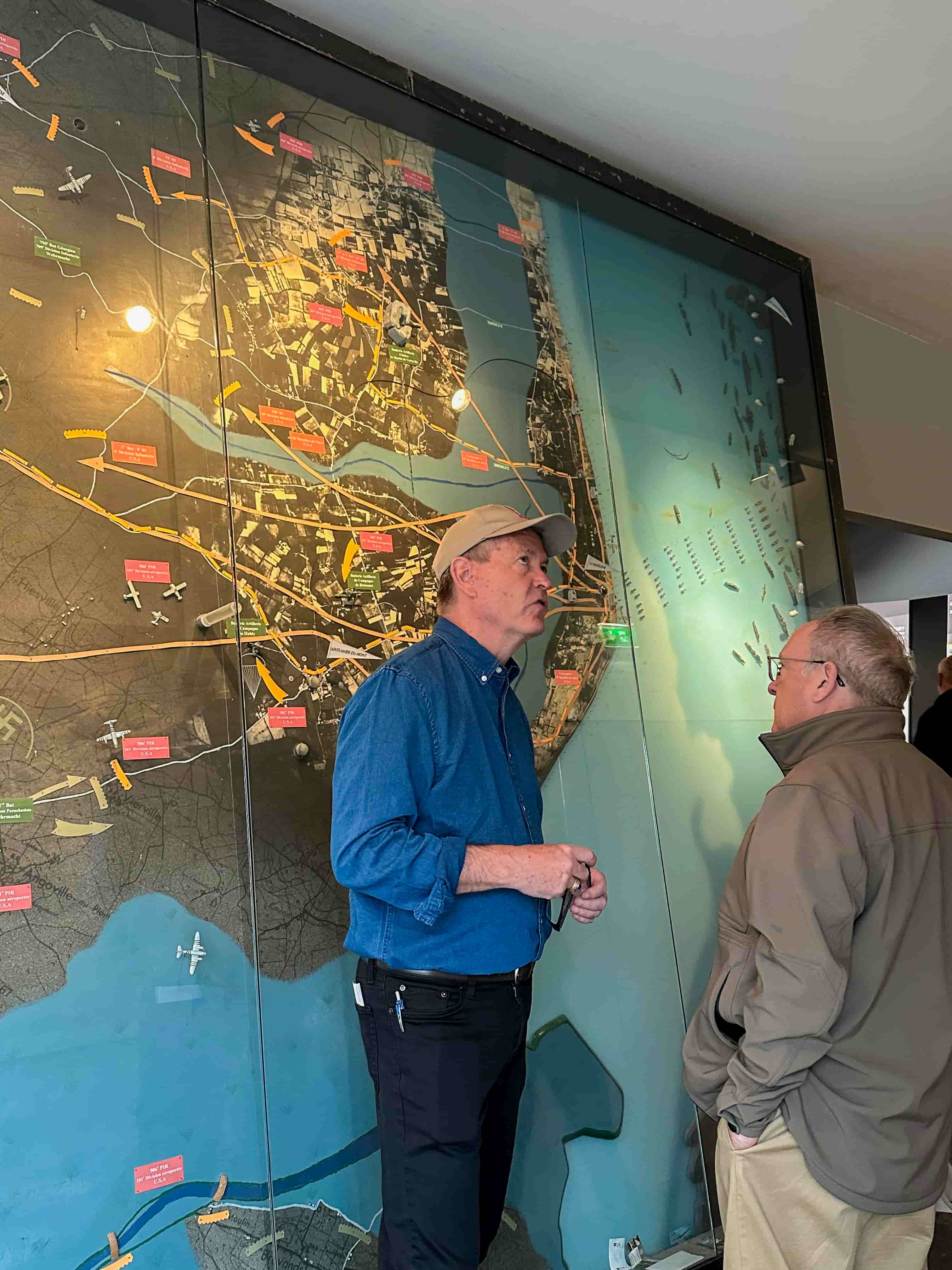 Guide explaining a large D-Day landings map inside a Normandy WWII museum