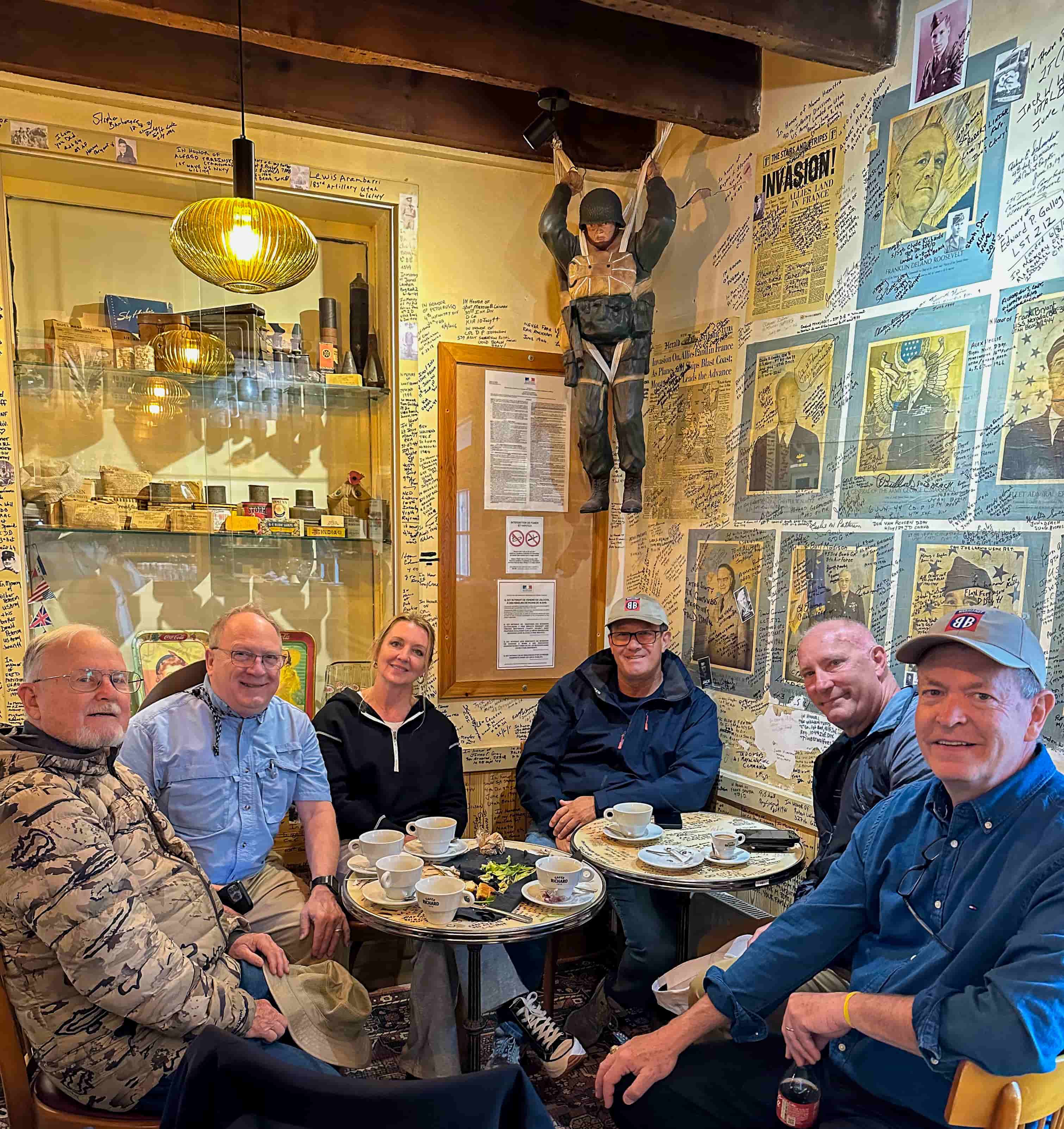 Tour group seated in a Normandy cafe covered with WWII photos and memorabilia