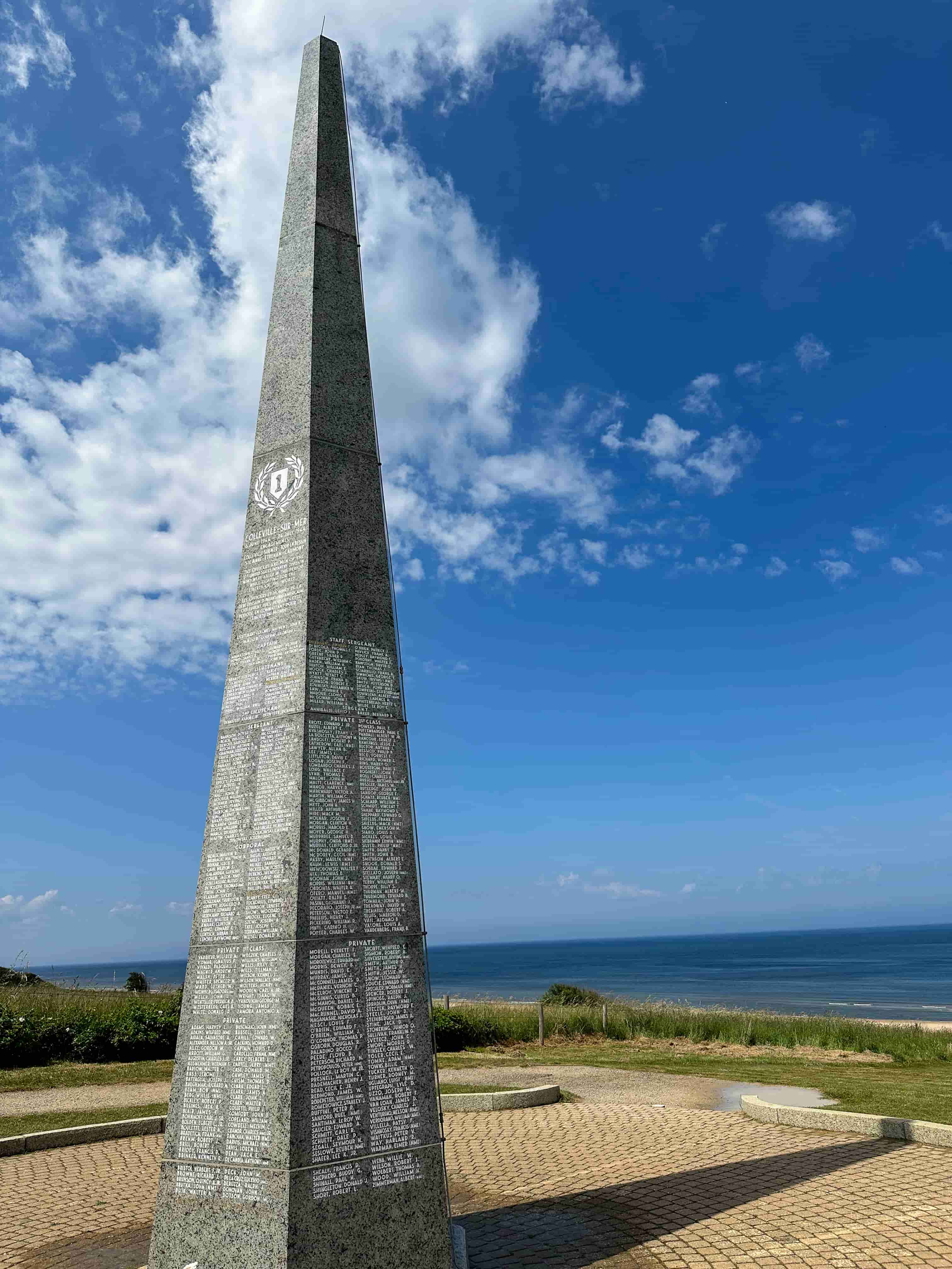 Granite memorial obelisk inscribed with names overlooking Omaha Beach in Normandy
