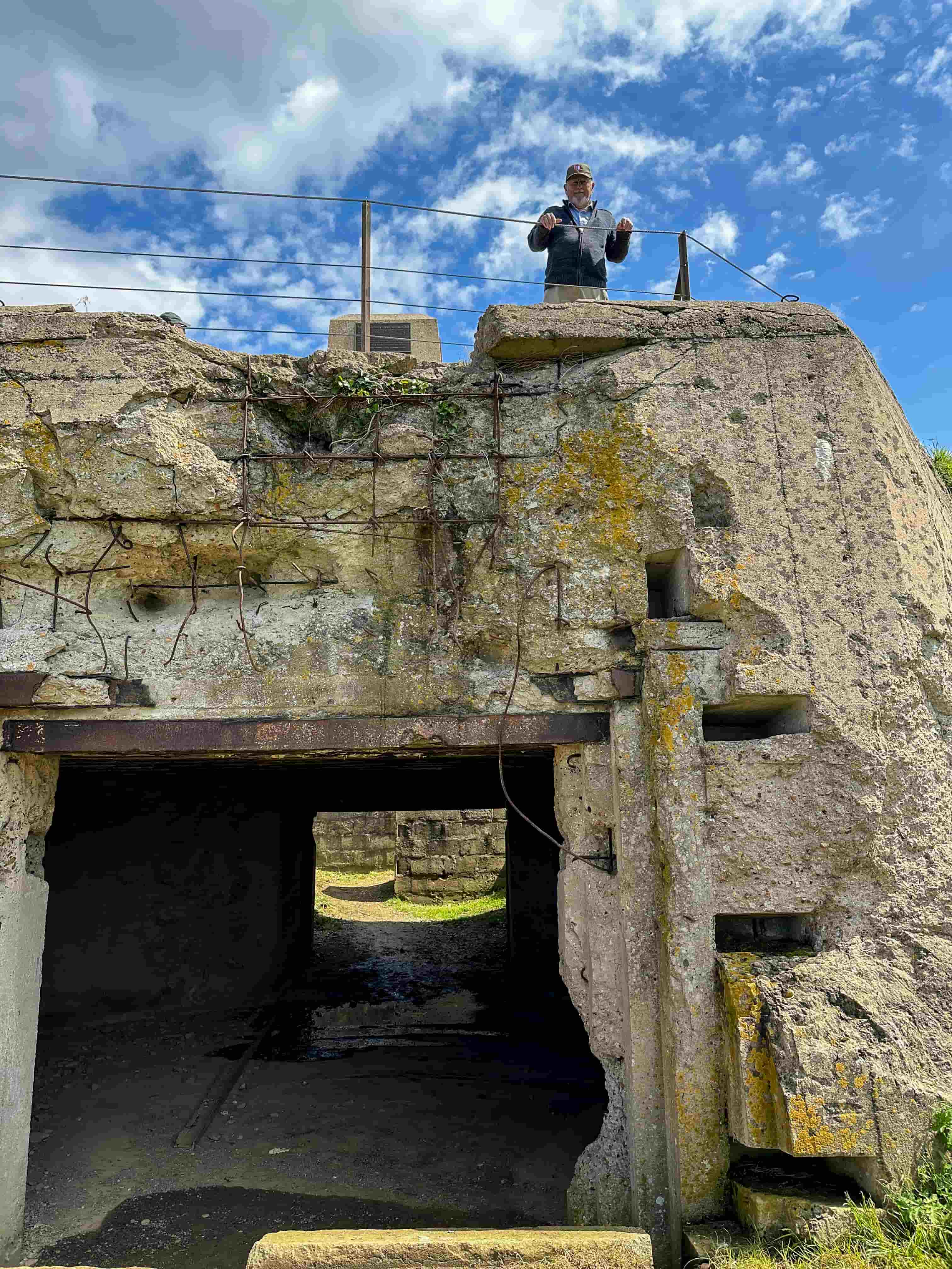 A traveler atop a ruined German bunker at a Normandy D-Day battery site