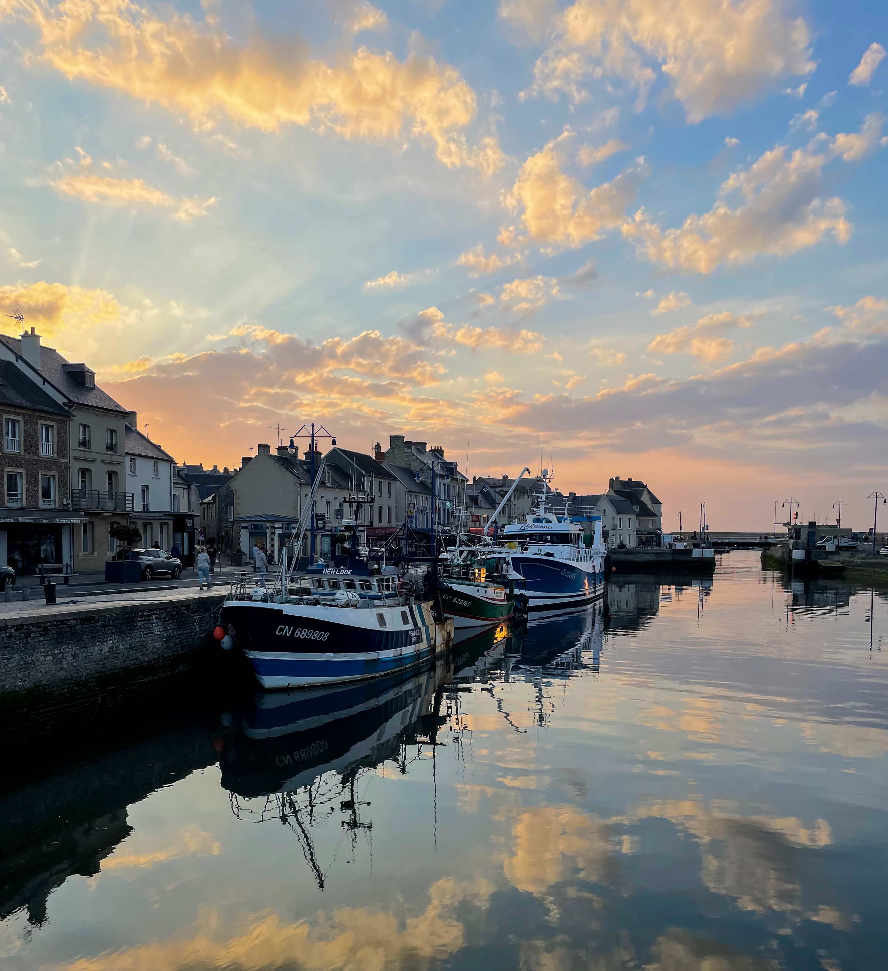 Fishing boats moored at a Normandy harbor at sunset during a WWII Normandy tour