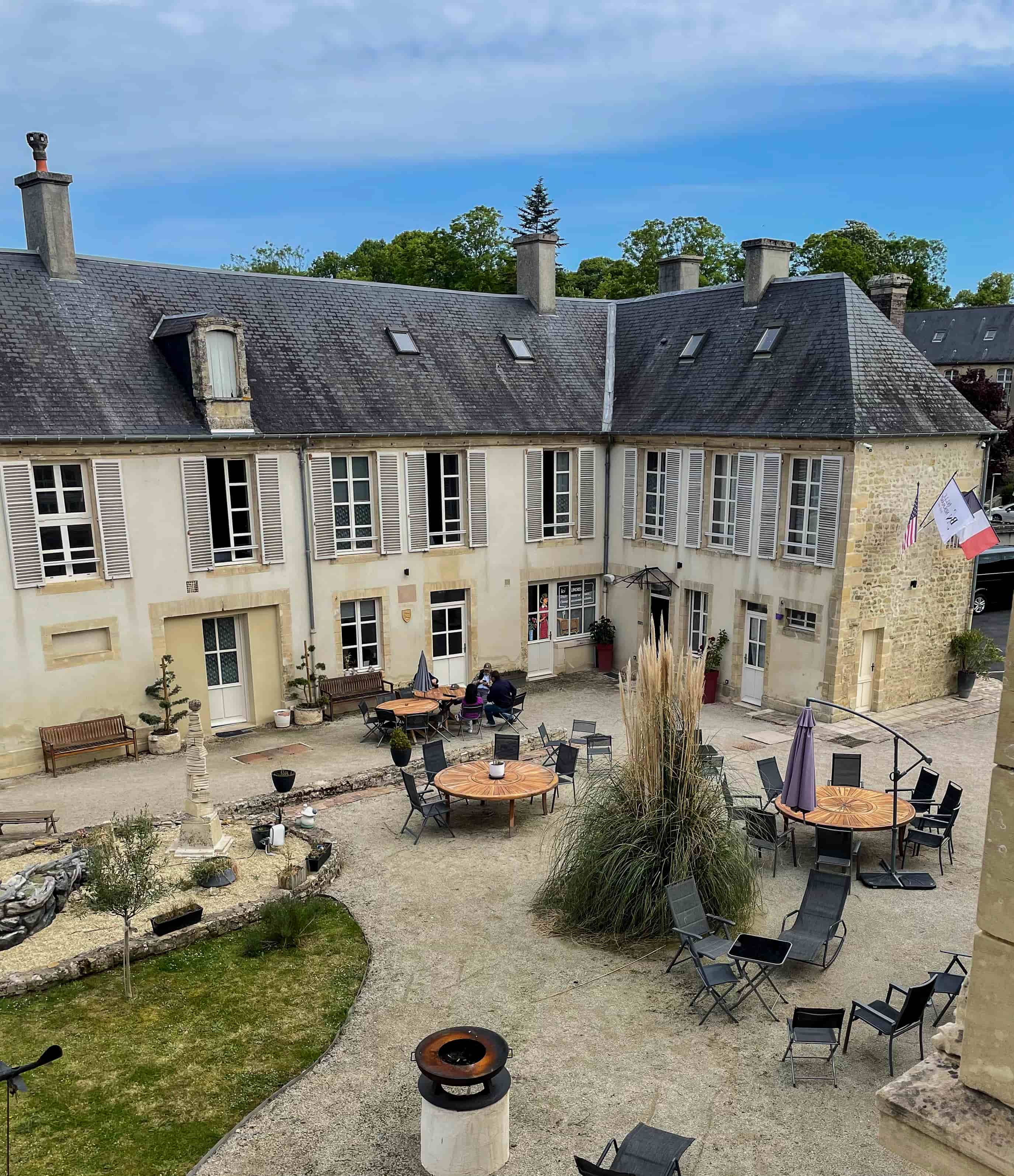 Courtyard of the group's Normandy tour hotel with cafe tables and US and French flags