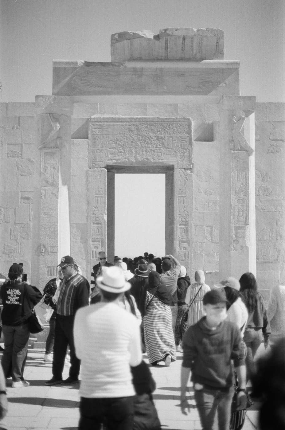 A tour group gathered at a temple gateway in the Theban hills
