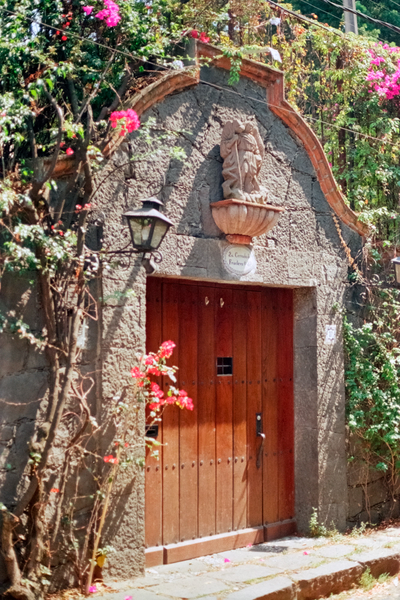 A carved stone doorway and wooden gate on a colonial Mexico City street