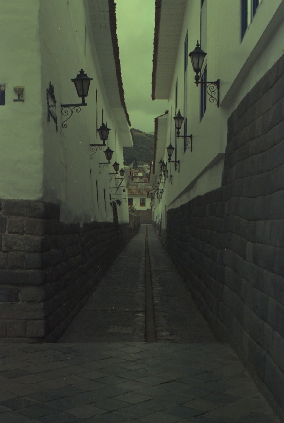 A narrow lane of whitewashed walls and iron lamps in Cusco