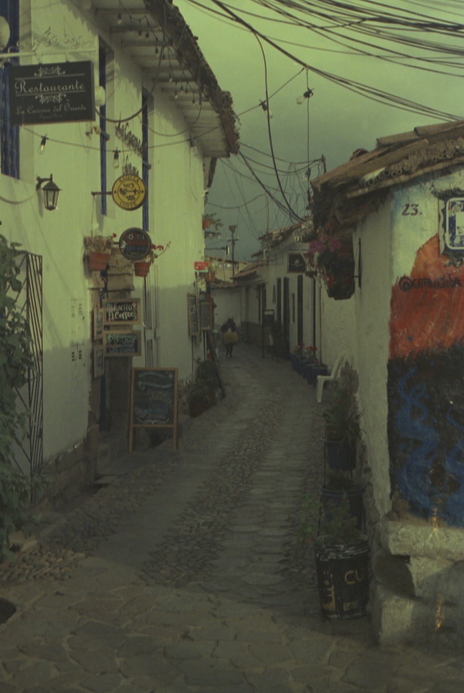 A narrow Cusco street of colonial houses under morning cloud