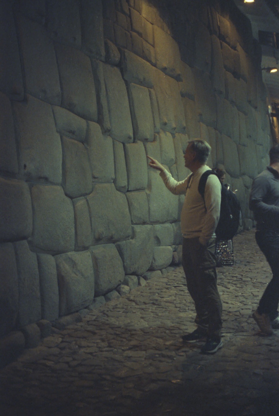 A traveler photographing the Inca stonework of a Cusco alley wall