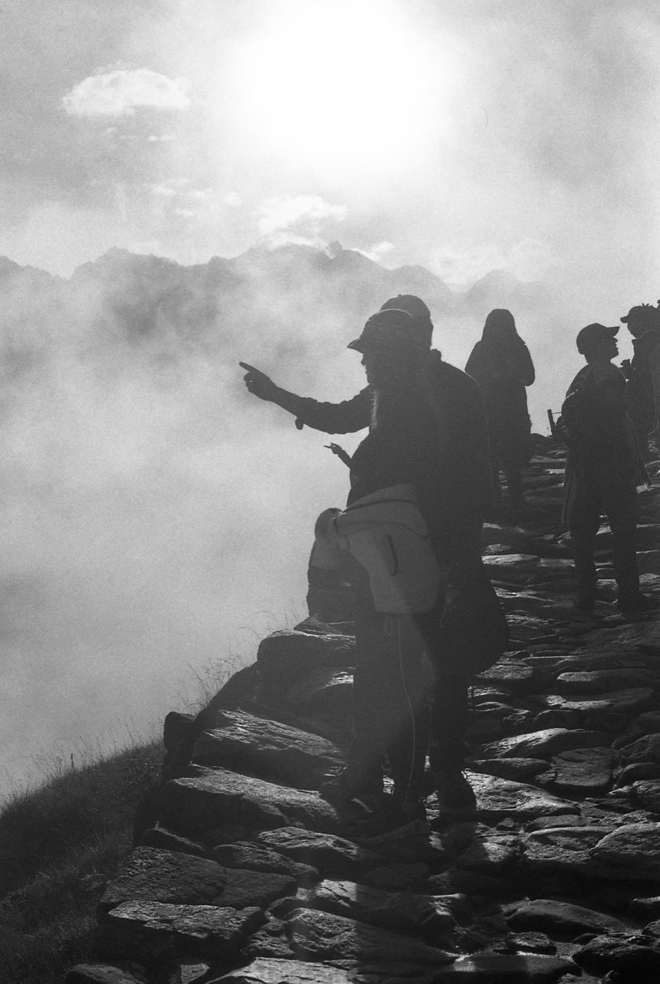 Travelers silhouetted against the sun above Machu Picchu
