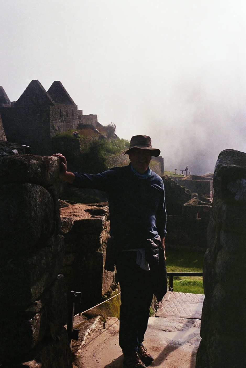 A traveler stepping through a stone gateway at Machu Picchu