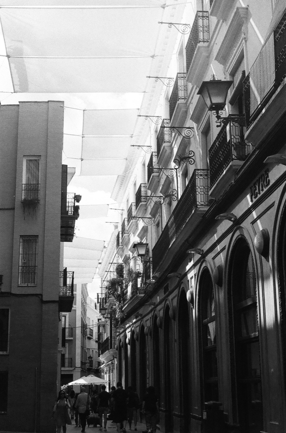 Balconies and sun awnings over a narrow Andalusian street, shot on black and white film